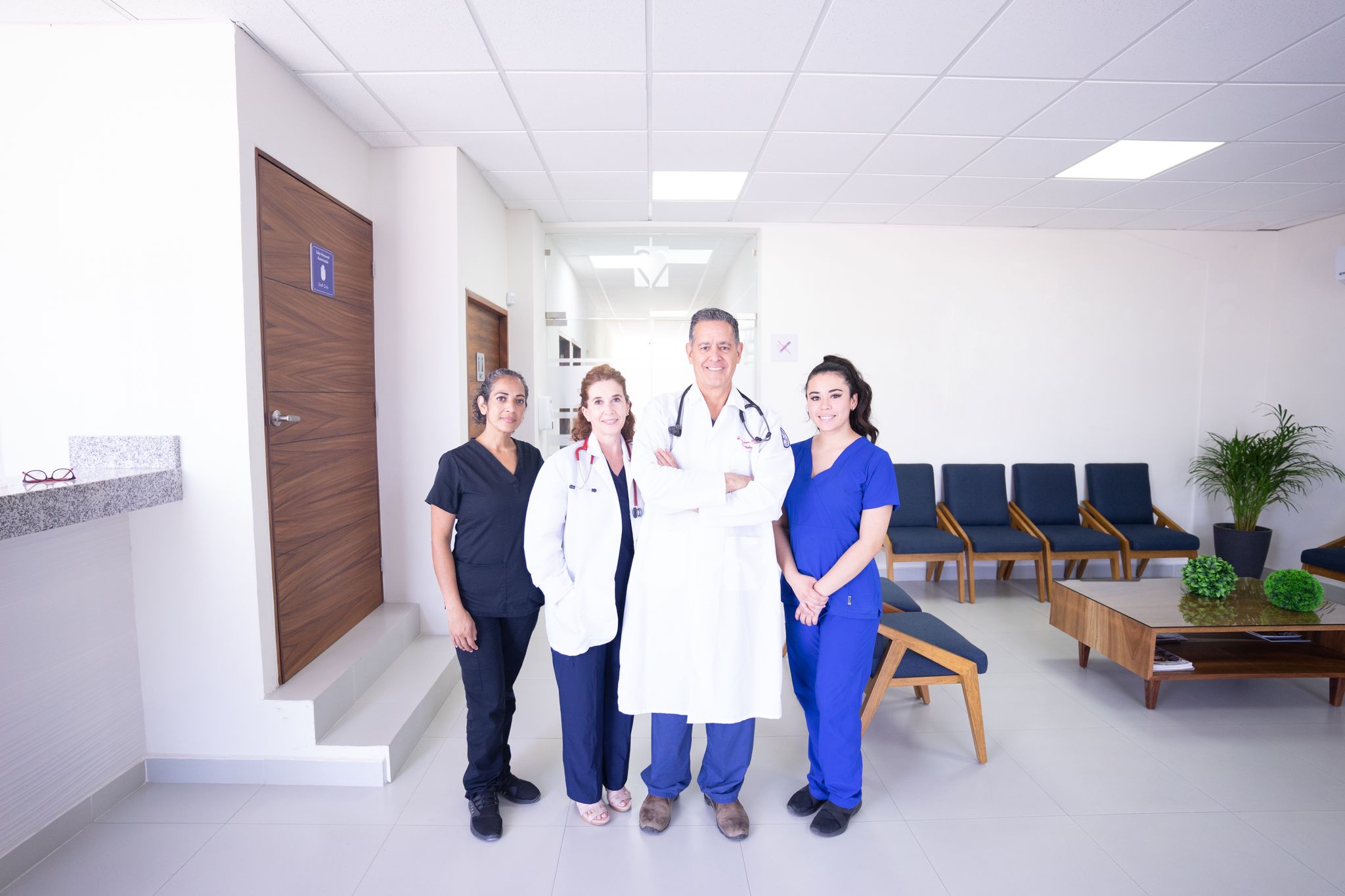 Diverse medical practitioners in uniforms, smiling in a modern hospital waiting area.