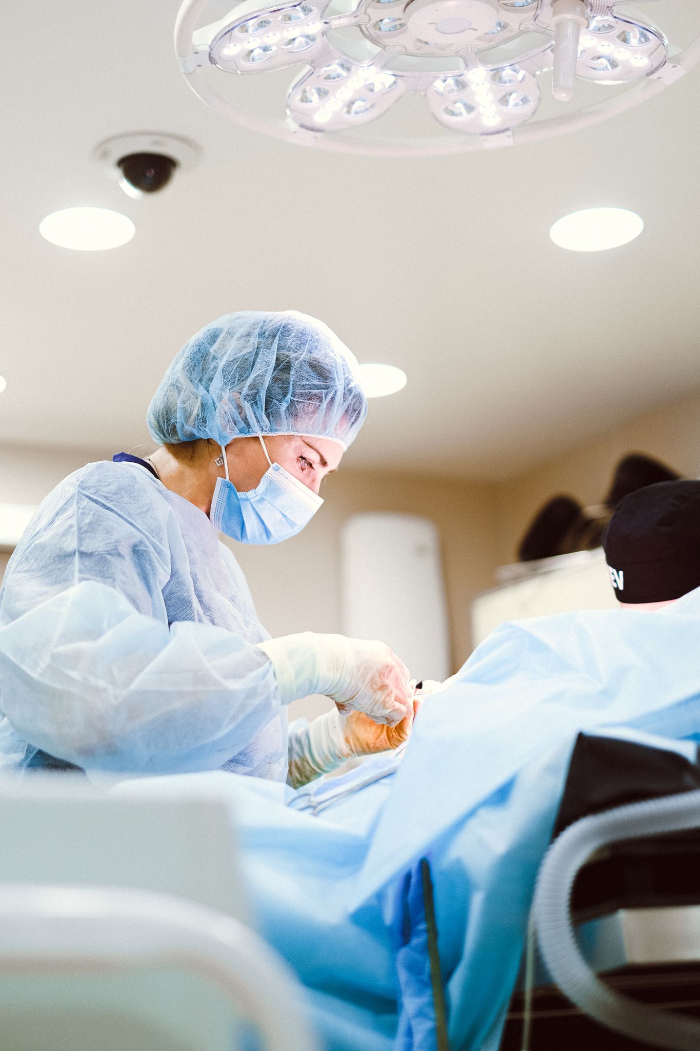 Medical professional performing surgery in sterile operating room setting.